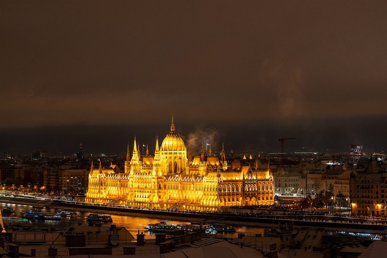 The Hungarian Parliament Building rising above snow-covered rooftops at night in winter
