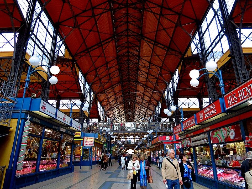 Interior of the Great Market Hall in Budapest showing the colorful painted-tile iron roof trusses and market stalls below